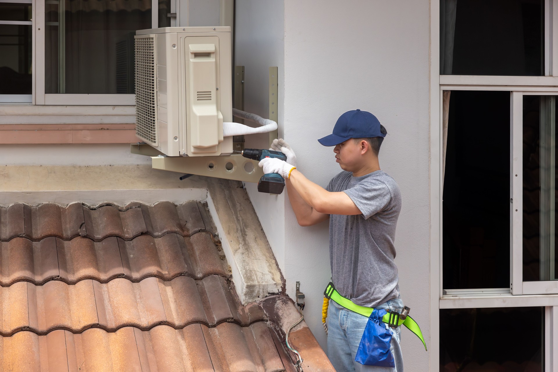 Technician  fixing air conditioner unit on outside wall.